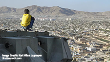Boy sitting in front of a view over Kabul